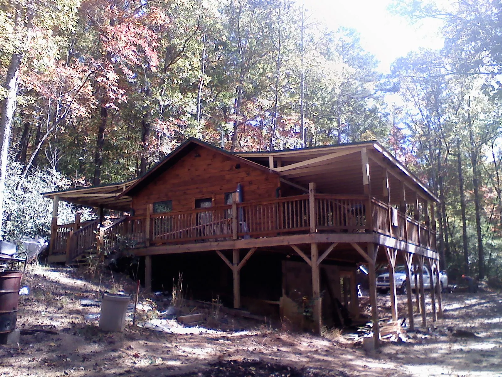 Log cabin with a wraparound porch and metal roof in the fall in Erie