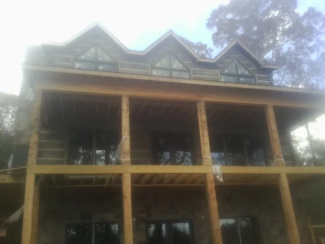 Dormers and porch framing on a large log home under construction — Roof Coating work by our crew in Erie