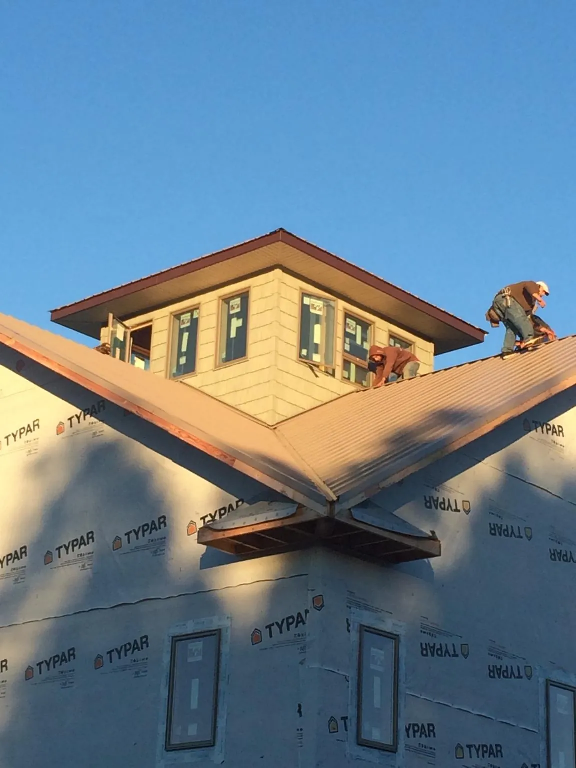 Roofers working around a rooftop cupola on a new metal roof at sunset — Roof Waterproofing in Erie by Roofing Brothers